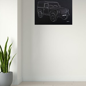 May include: Black canvas art print featuring a white line drawing of a Land Rover Defender. The artwork shows the vehicle's profile, including wheels, windows, and headlights. The license plate reads "ABC 123".
