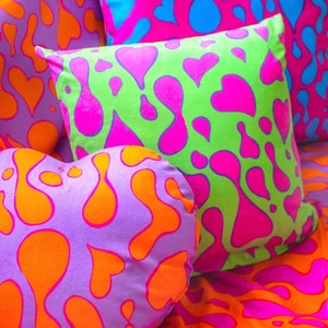 Puede incluir: Una colección de almohadas en forma de corazón de colores con un patrón abstracto único. Las almohadas están hechas de tela suave y presentan una combinación de colores brillantes rosa, verde, azul y naranja.