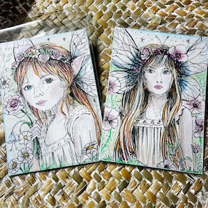 May include: Two watercolour illustrations of fairy-like figures with floral crowns and butterfly wings. The artwork features detailed faces, long hair, and delicate dresses, surrounded by flowers and greenery. The style is whimsical and ethereal.