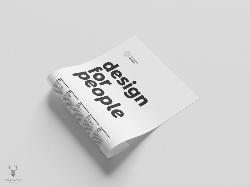 May include: A white sheet of paper with the text "design for people" printed in black bold letters. The paper is folded in half and the top edge is curled over.