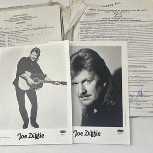 May include: Black and white photographs of Joe Diffie, one playing a guitar and the other a headshot. Documents and papers are in the background. The photographs are labeled "Joe Diffie" and "CAA".