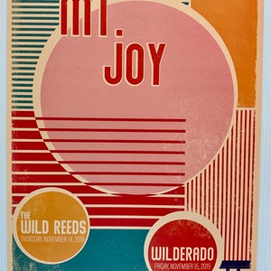 May include: A vintage-style concert poster for Mt. Joy at The Fillmore in San Francisco. The poster features the band's name in bold red letters over a pink circle, with additional text for The Wild Reeds and Wilderado. The poster has a retro design with a cream, red, orange, and blue color scheme.