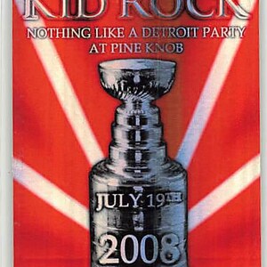 May include: A rectangular laminated all access pass featuring a red background with white radiating lines. The text reads KID ROCK, NOTHING LIKE A DETROIT PARTY AT PINE KNOB, JULY 19TH 2008, and ALL ACCESS. A silver trophy cup graphic is centered.
