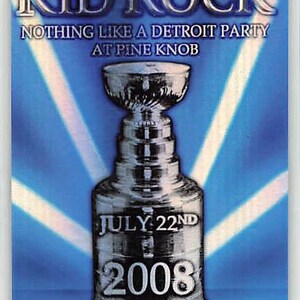 Puede incluir: Un pase de evento de plástico transparente con el texto plateado "KID ROCK". El pase incluye el texto "NOTHING LIKE A DETROIT PARTY AT PINE KNOB" y "JULY 22ND 2008". Un trofeo plateado está en el centro, con "ALL ACCESS" en la parte inferior.