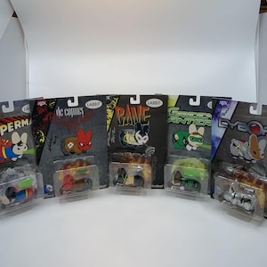 May include: Five blind box collectible figures featuring DC Comics characters. The figures are Superman, Red Hood, Bane, Green Lantern, and Cyborg. Each figure is in a clear plastic box with a colorful background and the character's name printed on the front.