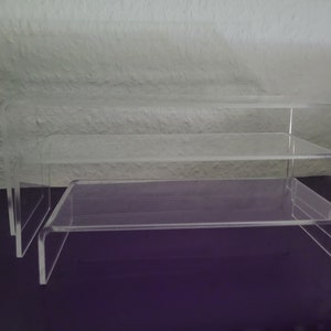 Puede incluir: Tres estantes de acrílico transparente apilados uno encima del otro. Los estantes están hechos de acrílico grueso y resistente y tienen un diseño moderno y minimalista.