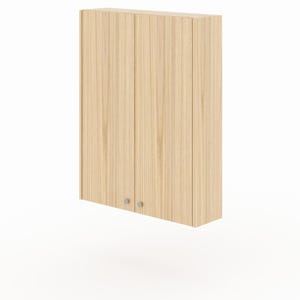 May include: A wall-mounted cabinet featuring a light wood grain finish and two vertical doors. Each door is equipped with a small, circular, silver-toned knob positioned near the bottom centre, providing a clean and functional storage solution.