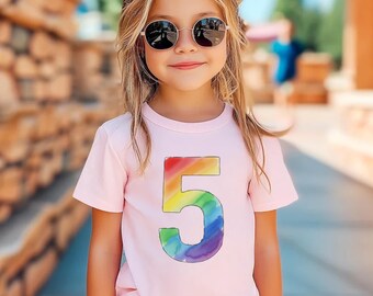 May include: A light pink t-shirt with a large, rainbow-colored number 5 on the front. The number is in a watercolor style. The person in the image is wearing sunglasses.