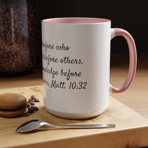 May include: White ceramic mug with a pink rim and handle. The mug features a black quote: "He who is before who is before others, knowledge before heavens, Matt. 10:32".