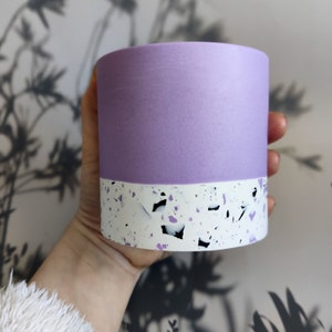 A purple and white ceramic planter with a speckled pattern. The planter is cylindrical and has a smooth, matte finish.