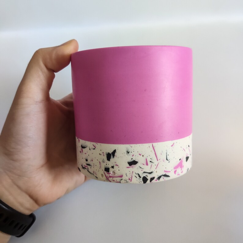 May include: A pink and white planter with a speckled pattern. The planter is made of concrete and has a smooth, matte finish.