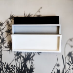 May include: Three rectangular trays stacked on top of each other. The top tray is black, the middle tray is light grey, and the bottom tray is white.