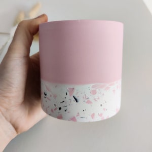 A pink and white terrazzo planter with a pink top and a white bottom with black and pink flecks.