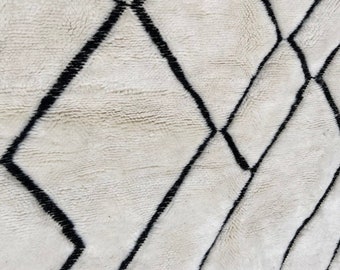 Könnte beinhalten: Weißer Teppich mit schwarzem Rautenmuster. Der Teppich ist aus Wolle und hat eine weiche, flauschige Textur.