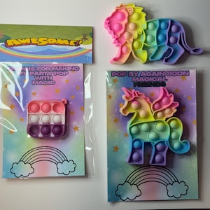 Puede incluir: Una colección de juguetes pop-it coloridos, que incluyen un león, un unicornio y uno pequeño de forma cuadrada. Los juguetes son de varios colores y están empaquetados con tarjetas que tienen texto como "AWESOME!" y "POP BY AGAIN SOON MAGICAL FRIENDS."