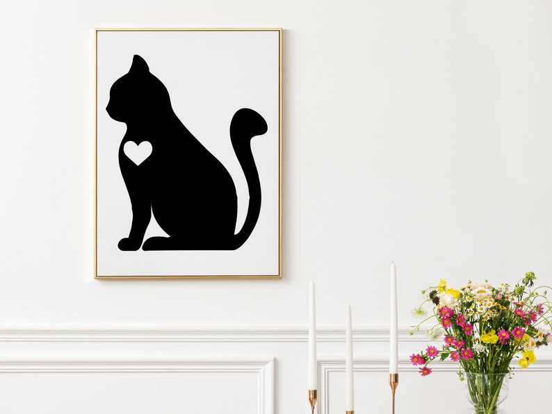 May include: Black and white silhouette of a cat with a heart on its chest. The cat is sitting with its tail curled around its body. The image is framed in a gold frame.