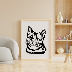 May include: A black and white silhouette of a cat's head, looking to the right, is framed in a simple wooden frame and hung on a light beige wall.