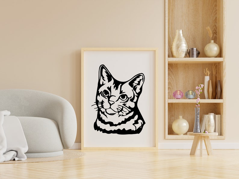 May include: A black and white silhouette of a cat's head, looking to the right, is framed in a simple wooden frame and hung on a light beige wall.