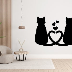 May include: Black silhouette of two cats with their tails intertwined to form a heart shape. The cats are facing away from each other, with their heads tilted slightly. There are small hearts floating above the cats.