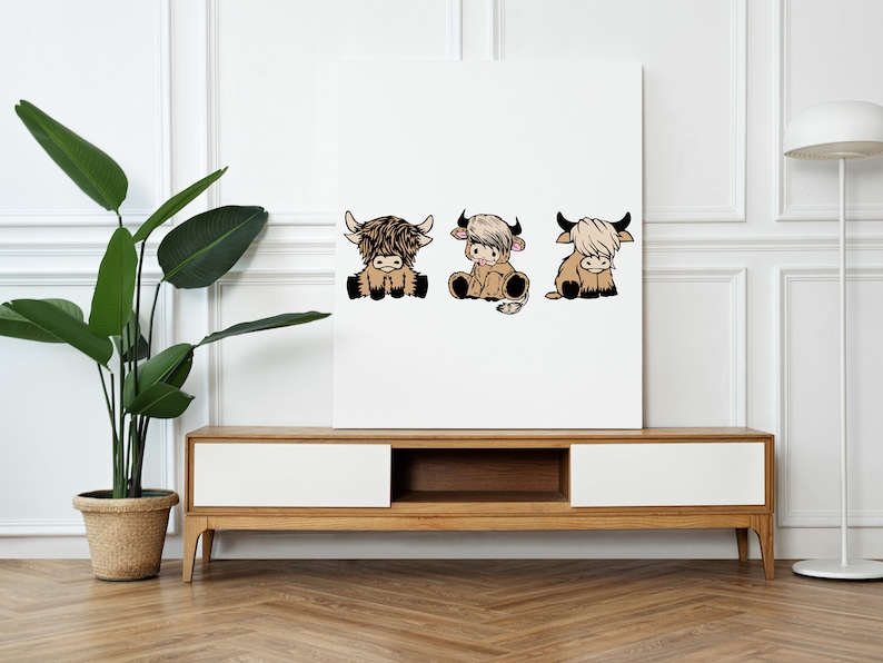 May include: Three cartoon Highland cows, each with a different expression, are depicted in a white frame. The cows are brown and white with fluffy fur. The frame is on a white wall above a wooden shelf.