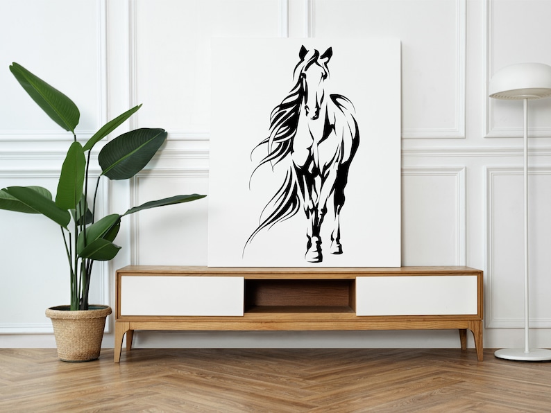 Op de afbeelding: Zwart-witte silhouet van een paard met een wapperende manen, afgedrukt op een wit canvas en tentoongesteld op een houten plank.