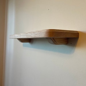 May include: A light wood shelf with rounded edges is mounted to a wall. The shelf is about 12 inches long and 4 inches wide.