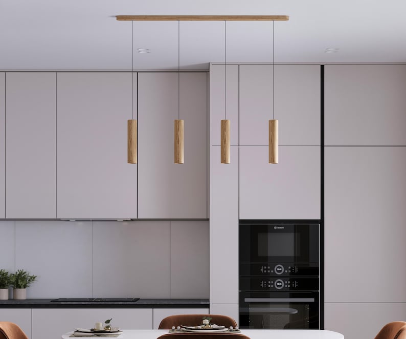 Linear oak pendant light above kitchen dining table. Handmade from solid wood with natural finish, this minimalist ceiling fixture suits Scandinavian, Japandi, and Nordic interiors. Ideal as wooden kitchen table light, oak hanging light bar, or natural wood ceiling light. Modern LED light fixture for warm, inviting spaces. Crafted oak lighting for stylish dining rooms and contemporary homes.