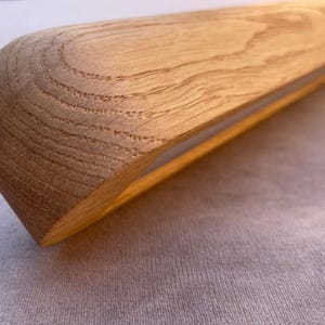 Puede incluir: Primer plano de un objeto de madera con un extremo redondeado. La veta de la madera es visible y el objeto es de color marr&oacute;n claro. El objeto parece ser parte de una estructura de madera m&aacute;s grande.