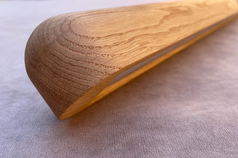 Puede incluir: Primer plano de un objeto de madera con un extremo redondeado. La veta de la madera es visible y el objeto es de color marr&oacute;n claro. El objeto parece ser parte de una estructura de madera m&aacute;s grande.