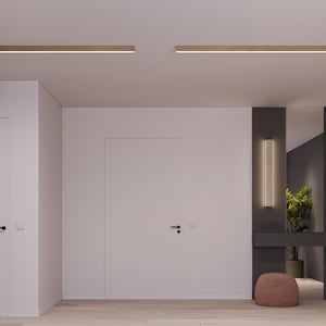 May include: Contemporary interior design with two long, rectangular wooden light fittings on the ceiling. The room has white walls, dark grey accents, and a wooden floor. A small pink ottoman and potted plants add colour.