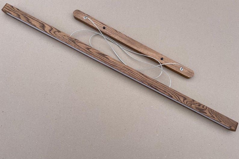 Puede incluir: Dos barras de madera rectangulares y largas para colgar p&oacute;steres con un prominente patr&oacute;n de veta de madera marr&oacute;n oscuro. Cada barra incluye un hilo met&aacute;lico fino de color plateado unido a la parte superior para colgar.