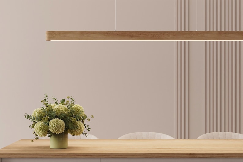 Solid wood linear pendant light above dining table with floral arrangement – modern oak ceiling lighting in Japandi interior