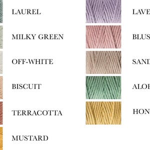 K&ouml;nnte beinhalten: Eine Farbkarte mit 10 verschiedenen Garnfarben, wobei die Namen der einzelnen Farben unter dem Garn aufgef&uuml;hrt sind: Lorbeer, Milchig Gr&uuml;n, Off-White, Keks, Terrakotta, Senf, Lavendel, Rouge, Sand, Aloe, Honig.