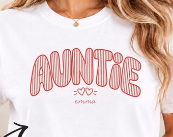 Könnte beinhalten: Ein weißes kurzärmeliges T-Shirt mit dem roten Schriftzug AUNTIE in einer fetten, gestreiften Schriftart. Unter dem Text befinden sich zwei kleine rote Herzen und der personalisierte Name emma in einer kleineren roten Schreibschrift.