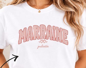Könnte beinhalten: Ein weißes Kurzarm-T-Shirt mit dem roten Schriftzug MARRAINE in einer gestreiften College-Schriftart, darunter zwei kleine Herzen und der Name juliette in einer kleineren, roten Schreibschrift.