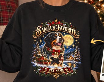Könnte beinhalten: Ein schwarzes Sweatshirt mit Rundhalsausschnitt, das eine Grafik eines Berner Sennenhundes, eine Winterlandschaft sowie den Text "SANTA'S FAVORITE" und "PET NAME" zeigt. Ein kleiner Einschub zeigt ein Hundefoto mit "UPLOAD YOUR ORIGINAL PHOTO".