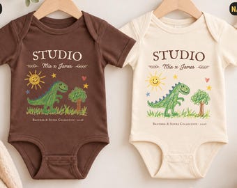 Könnte beinhalten: Zwei kurzärmelige Babybodys, einer in Braun und einer in Naturfarben, mit dem Text STUDIO, Mia x James und BROTHER & SISTER COLLECTION 2024. Die Grafik zeigt einen grünen Dinosaurier, eine gelbe Sonne, einen Baum und ein kleines rotes Herz.