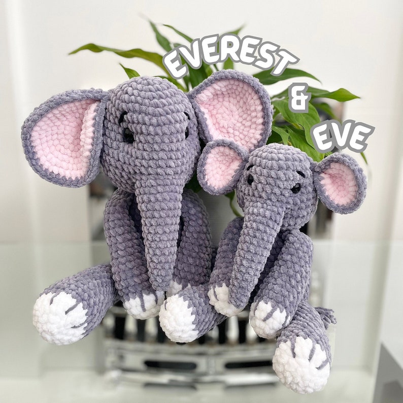 Puede incluir: Dos juguetes de elefante de peluche gris hechos a crochet con orejas rosas. El elefante m&aacute;s grande est&aacute; etiquetado como "Everest" y el m&aacute;s peque&ntilde;o como "Eve".