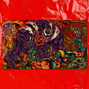 May include: A rectangular desk mat featuring a vibrant comic book illustration of Venom, Wolverine, and Doctor Doom in a battle scene. The artwork includes the text GOBLINBIZ in the upper right corner, with bold purple, green, and orange colours.