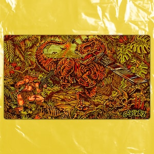May include: A rectangular, illustrated mousepad featuring a T-Rex with a sword and gun, facing a warrior in a jungle setting. The color palette includes shades of orange, brown, and green. The text "GOBLIBZ" is in the bottom right corner.