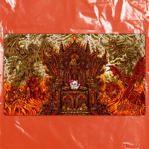May include: A rectangular playmat featuring a cartoon cat wearing a pink bow, seated on a throne amidst a fiery, hellish landscape. The design includes demons, flames, and the text "GOBLINBIZ" in the lower right corner.