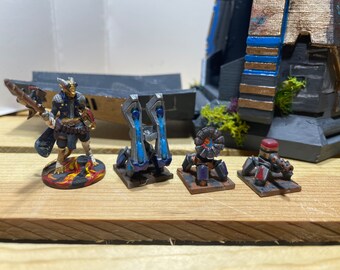 May include: A painted miniature figurine of a humanoid with reptilian features holding a weapon, along with four other painted miniatures of futuristic weaponry on bases.