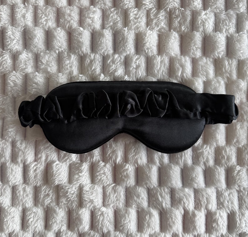 Pu&ograve; includere: Una mascherina per dormire di colore nero tinta unita, caratterizzata da una copertura oculare liscia e sagomata e da un cinturino elastico nero abbinato con una texture in tessuto arricciato e increspato. Il design &egrave; uniforme nel colore.