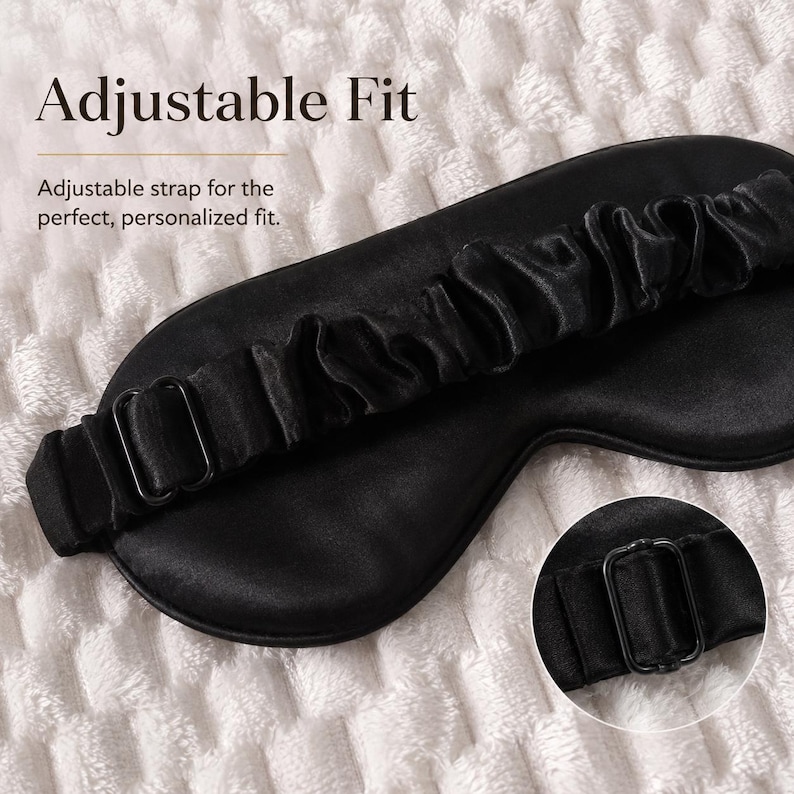 Pu&ograve; includere: Una mascherina per dormire nera con una finitura liscia e satinata e un cinturino elastico arricciato. Il cinturino &egrave; dotato di una fibbia scorrevole in metallo nero per la regolazione. Il testo sull'immagine recita: Adjustable Fit. Adjustable strap for the perfect, personalized fit.