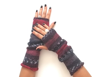 May include: A pair of fingerless gloves featuring a knitted texture with horizontal stripes in shades of deep red, dark purple, charcoal gray, and white. The gloves extend from the knuckles down to the mid-forearm with a ribbed cuff.