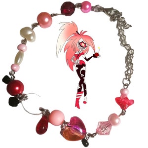 May include: A pink and red beaded bracelet with a silver chain and a heart-shaped charm. The bracelet features various beads, including pink, red, white, and clear beads.