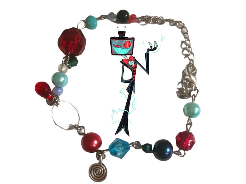 May include: A silver chain bracelet with red, blue, and green glass beads. The bracelet features a charm of a cartoon character with a television screen for a head. The character is wearing a black suit and a red bow tie.