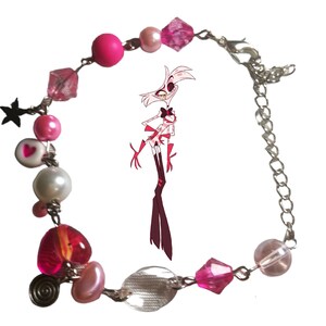 May include: A pink and silver charm bracelet with a variety of beads, including hearts, stars, and pearls. The bracelet also features a clear glass bead and a pink and silver charm with a cartoon character.