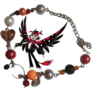 May include: A silver chain bracelet with red, orange, white, and black beads. The bracelet has a heart charm, a spiral charm, and a charm with a cartoon character with black wings and a red hat.