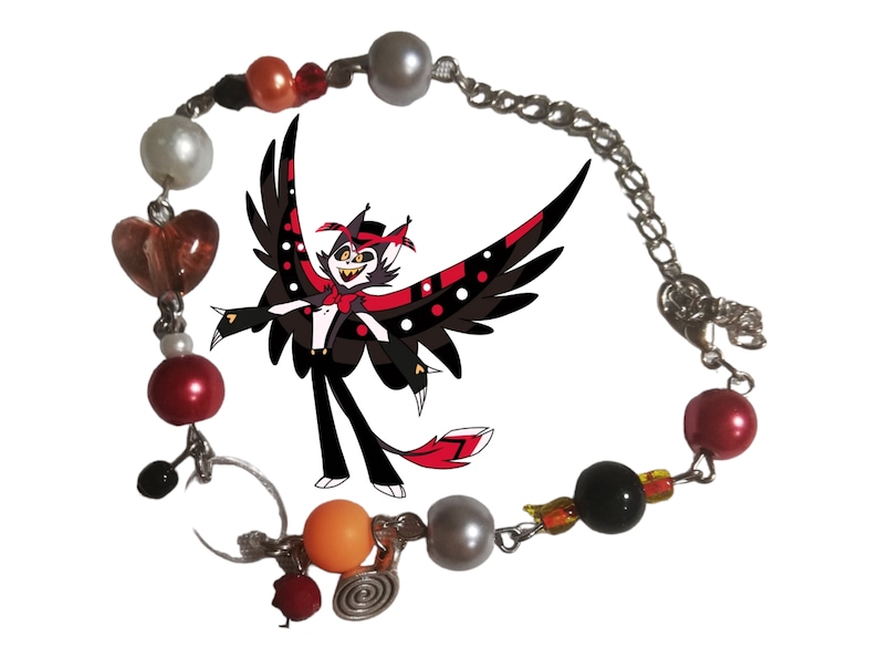 May include: A silver chain bracelet with red, orange, white, and black beads. The bracelet has a heart charm, a spiral charm, and a charm with a cartoon character with black wings and a red hat.